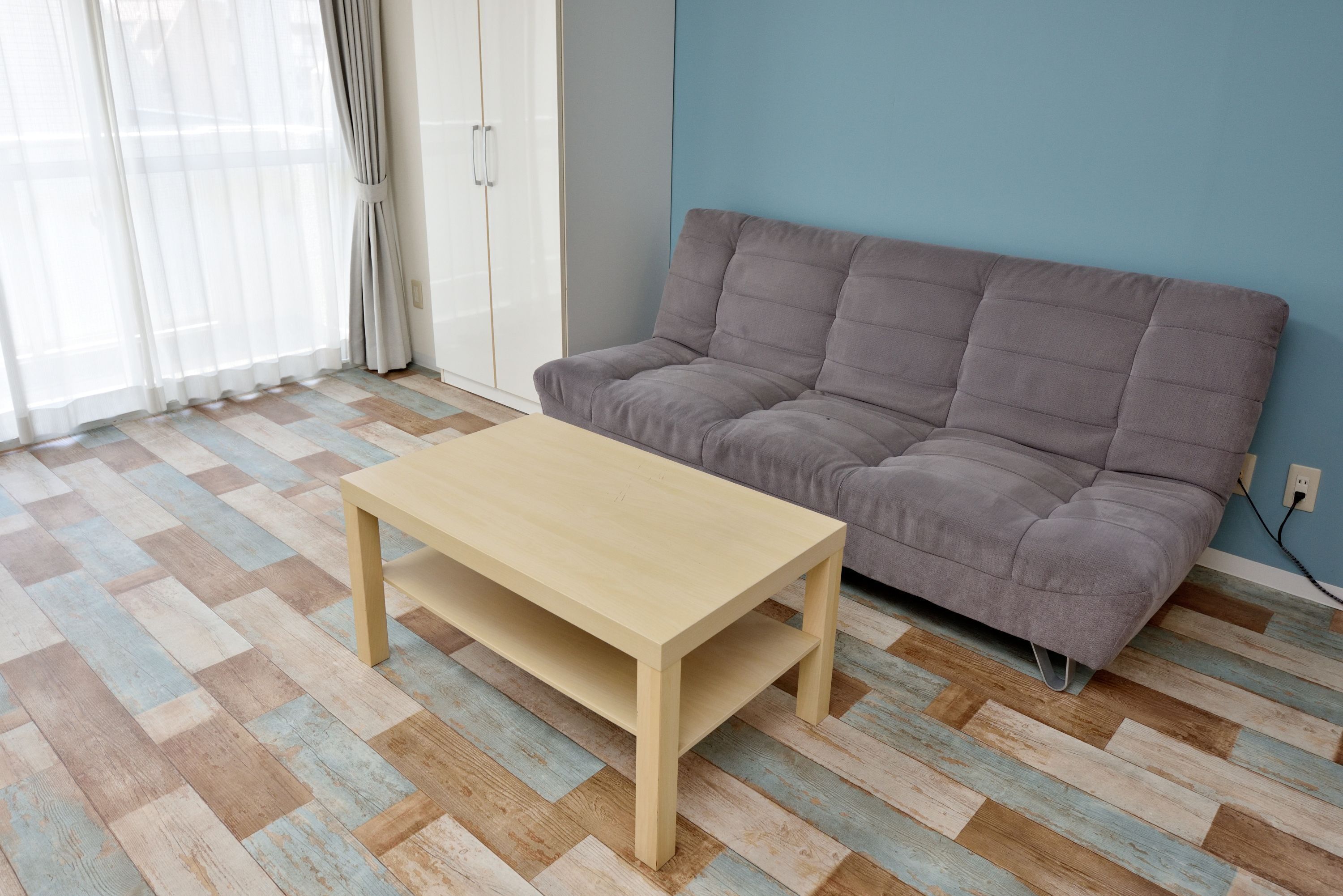 A room with a sofa, a wooden coffee table, and a patterned floor.