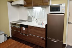 A compact kitchen with a microwave, dishwasher, and a refrigerator. - Wallaby House (Kawaguchi)