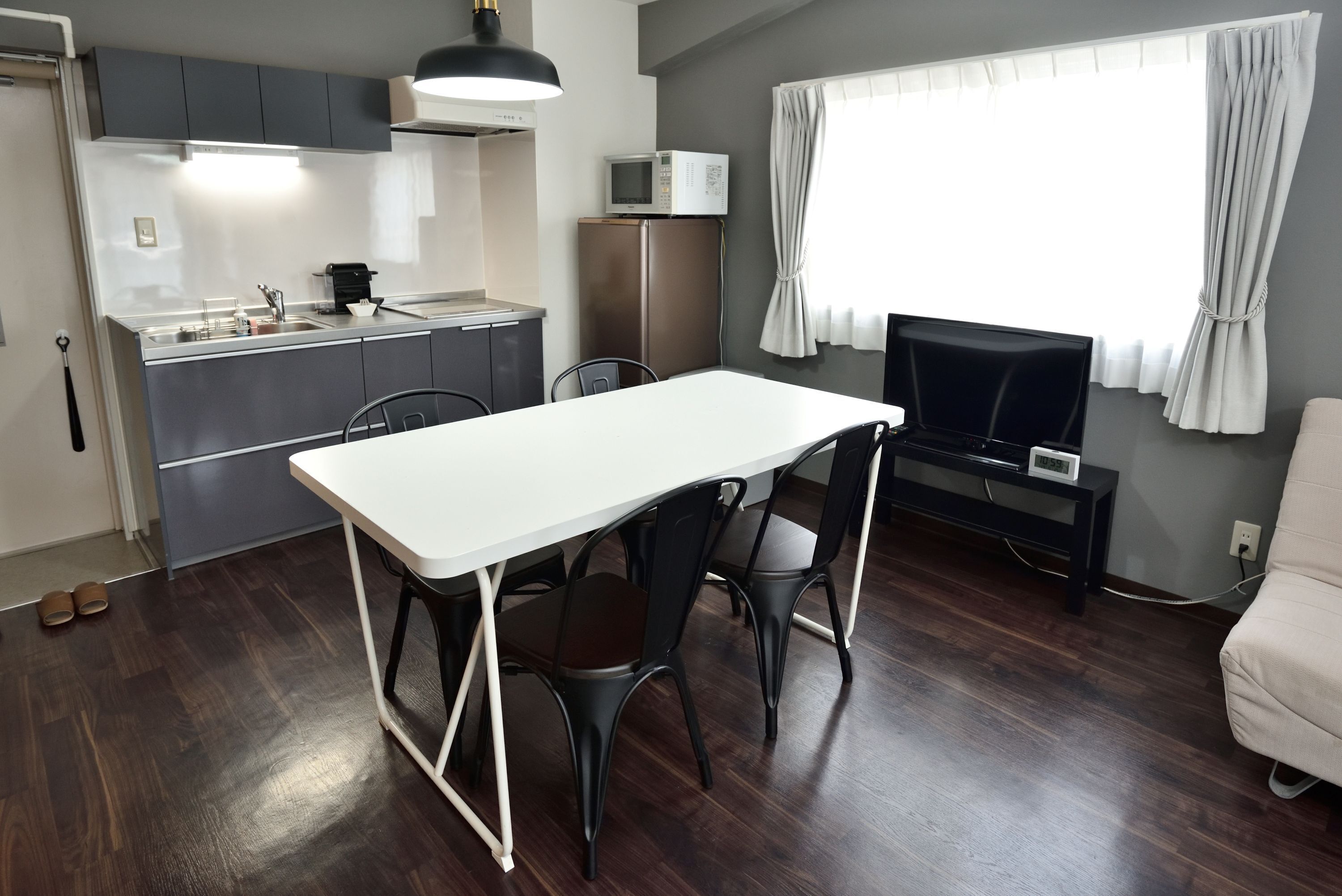 Un espacio habitable compacto con kitchenette, comedor y televisor.