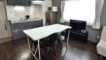 Un espacio habitable compacto con kitchenette, comedor y televisor.