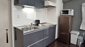 Uma cozinha compacta com uma pia de aço inoxidável, uma cafeteira, micro-ondas e geladeira.