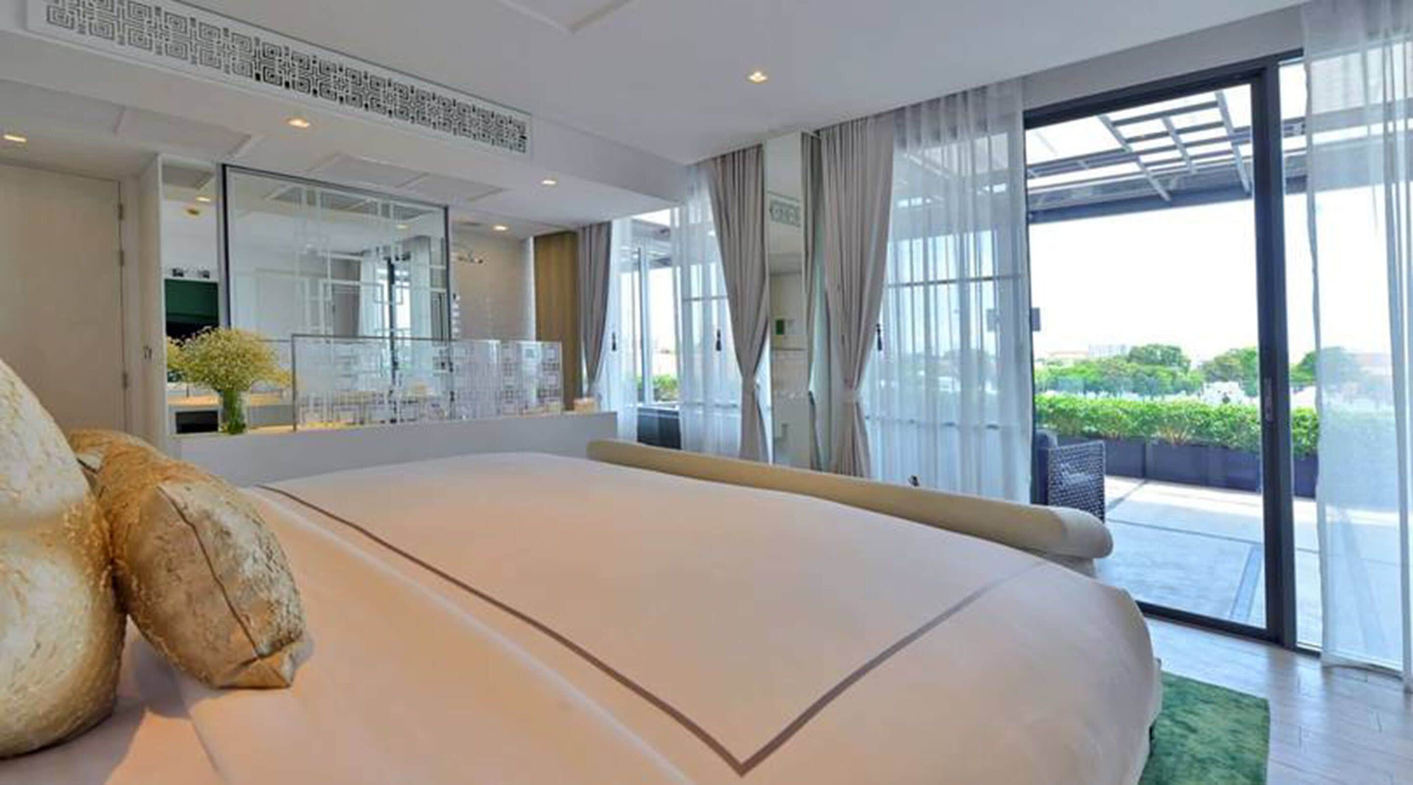Une chambre d’hôtel moderne avec un grand lit, un balcon offrant une belle vue et une grande fenêtre.