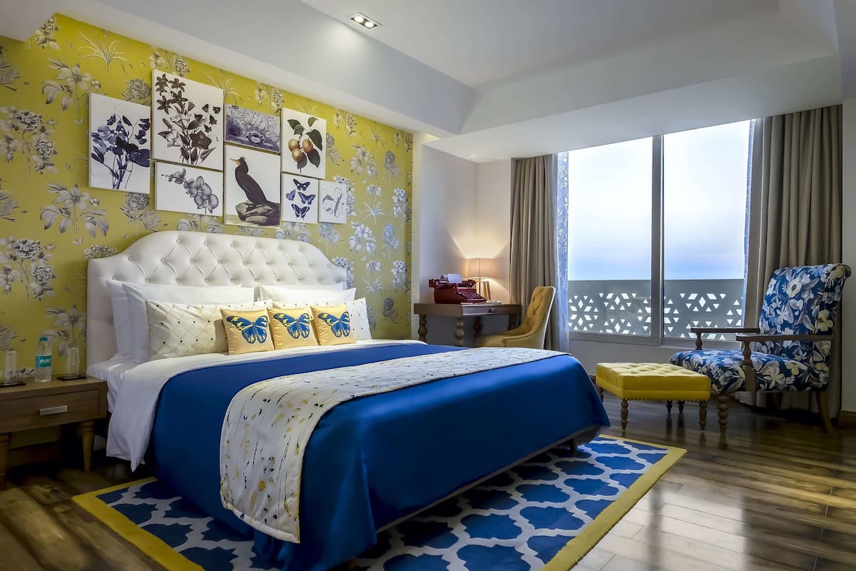 A hotel room with a large bed, a desk, a chair, and a view of the sea.