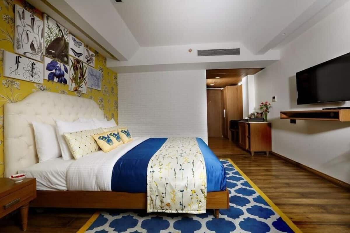 A bedroom with a bed, a TV, and a wall with botanical prints.