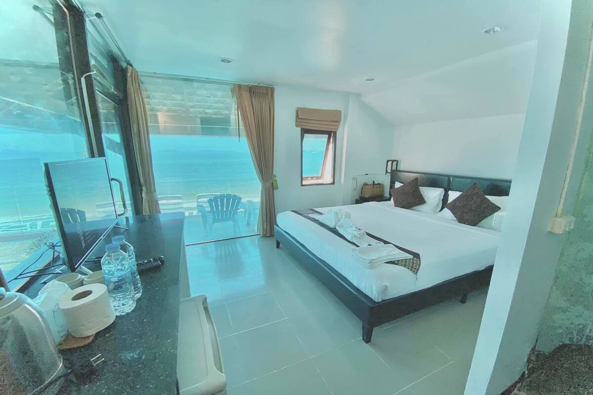 Habitación de hotel con cama, escritorio con silla, ventana con vistas y una mesita con artículos de aseo.