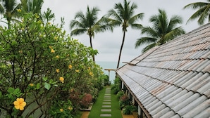 A pathway leading to a building with a corrugated metal roof, surrounded by lush greenery and palm trees. - The Shore Samui (Koh Samui)