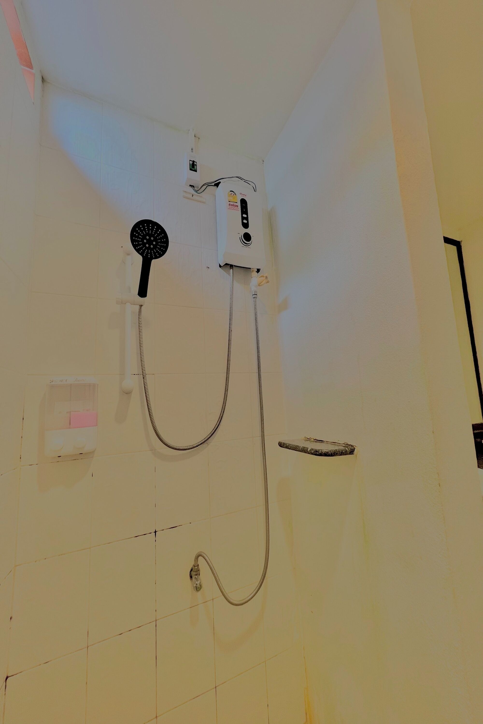 Une douche équipée d’un pommeau de douche à main, d’un panneau de commande fixé au mur et d’un pommeau de douche à main monté sur un support mural.