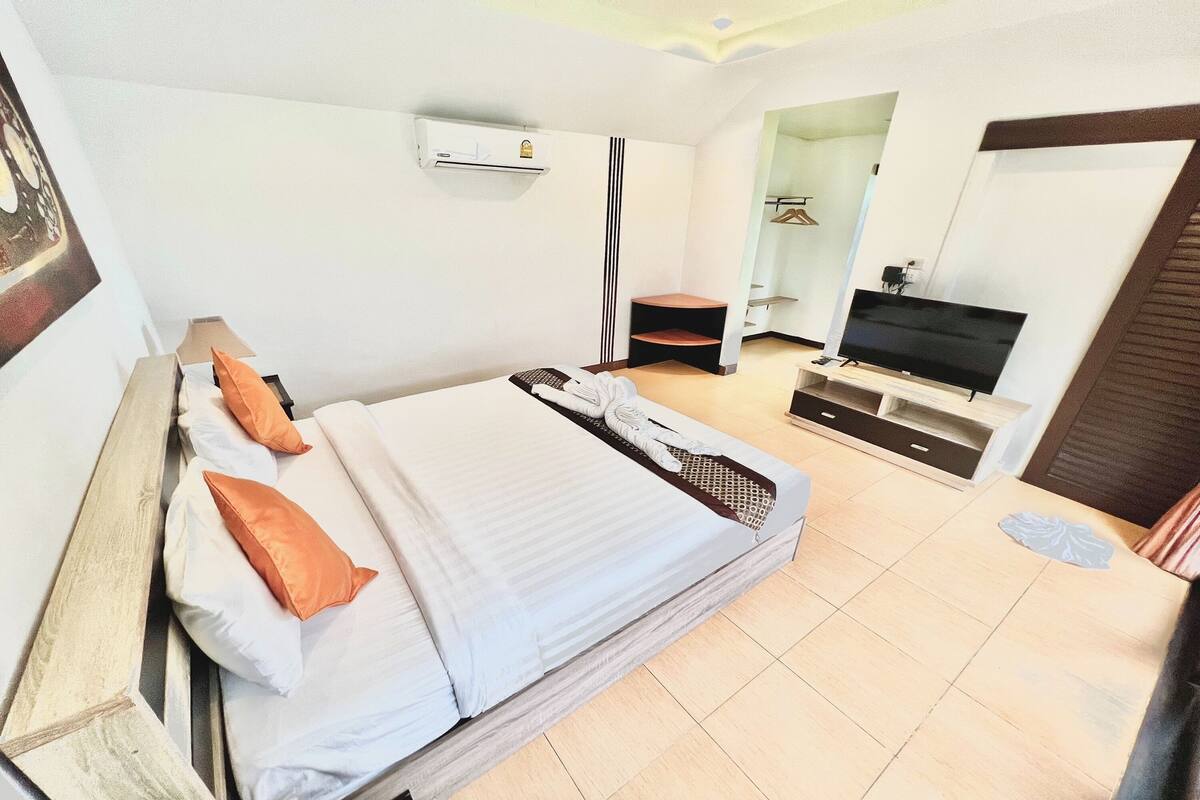 Habitación de hotel con cama, televisor, armario y aire acondicionado.