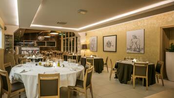 A restaurant with round tables, wooden chairs, and artwork on the walls.