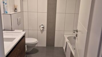 Et moderne badeværelse med hvid vask, toilet og badekar.