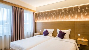 A hotel room with two beds, a wooden headboard with a floral pattern, a nightstand with a glass, and a window with sheer curtains. - Hotel Bon Repos (Consdorf)