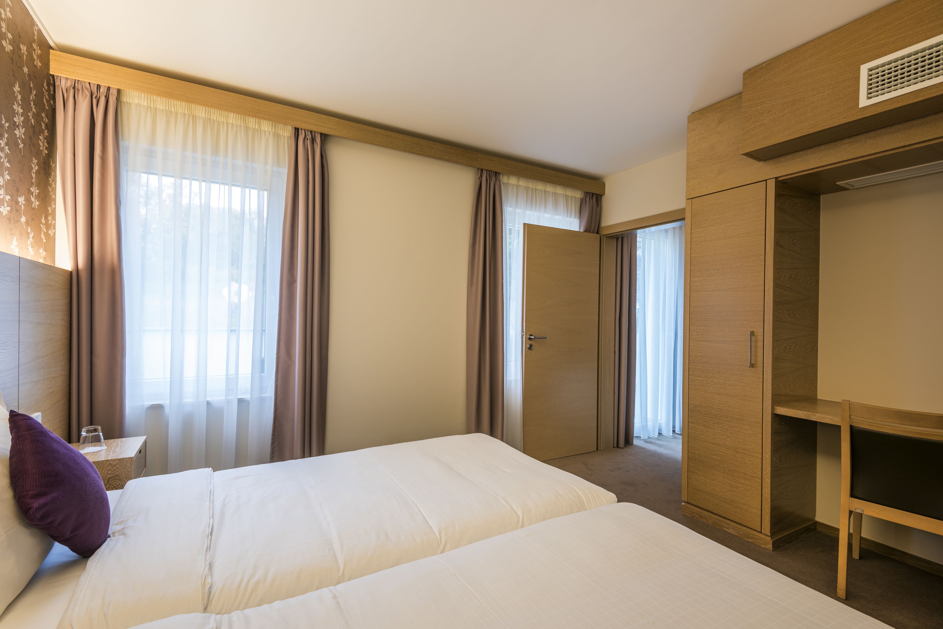 Hotellihuone, jossa on suuri sänky, vaatekaappi ja työpöytä.