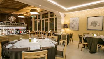Ein Restaurant mit Holzeinrichtung, einer Bar mit Weinflaschen und gerahmten Kunstwerken an den Wänden.