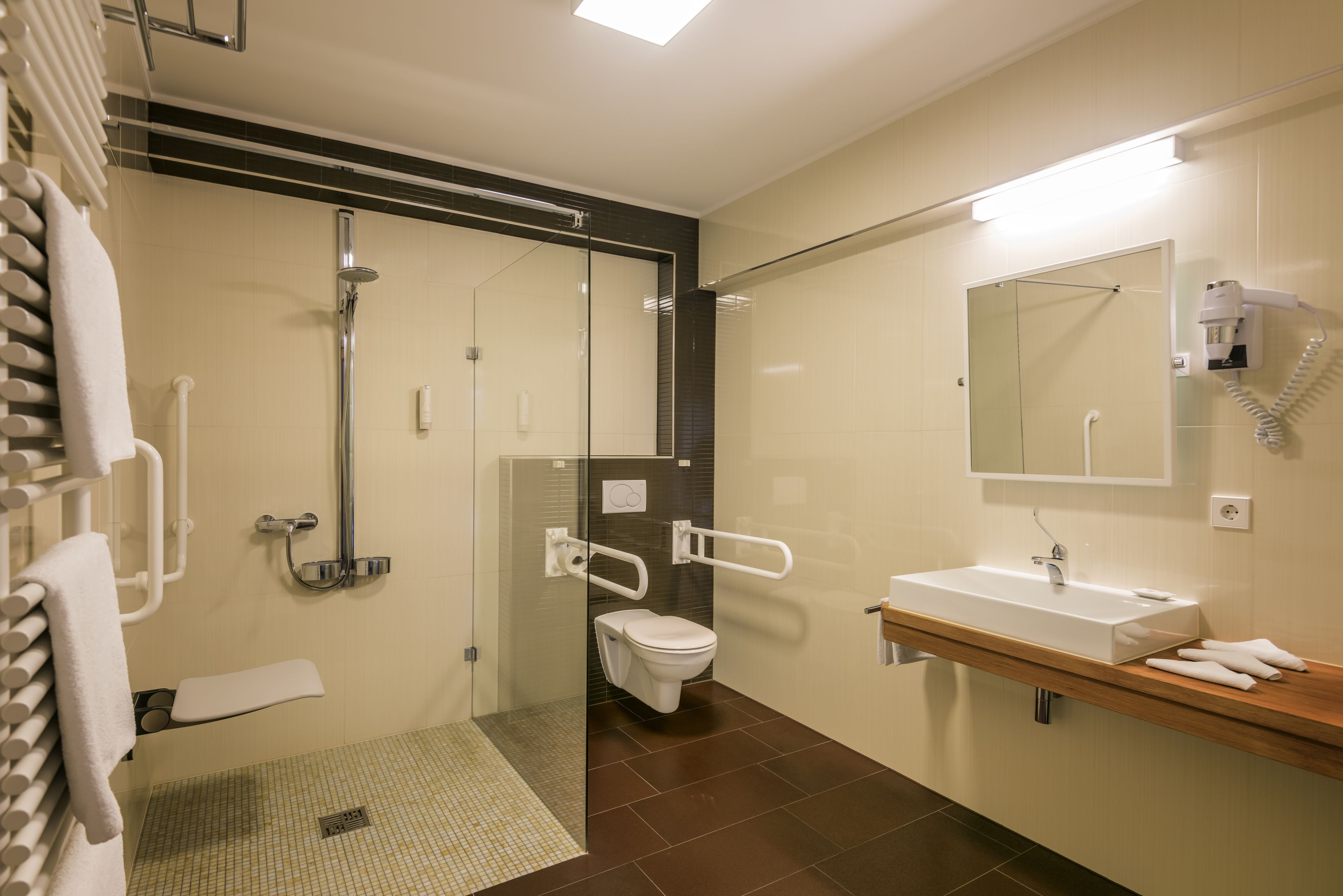 Un baño moderno con cabina de ducha de vidrio, inodoro blanco, lavabo con espejo y toallero.