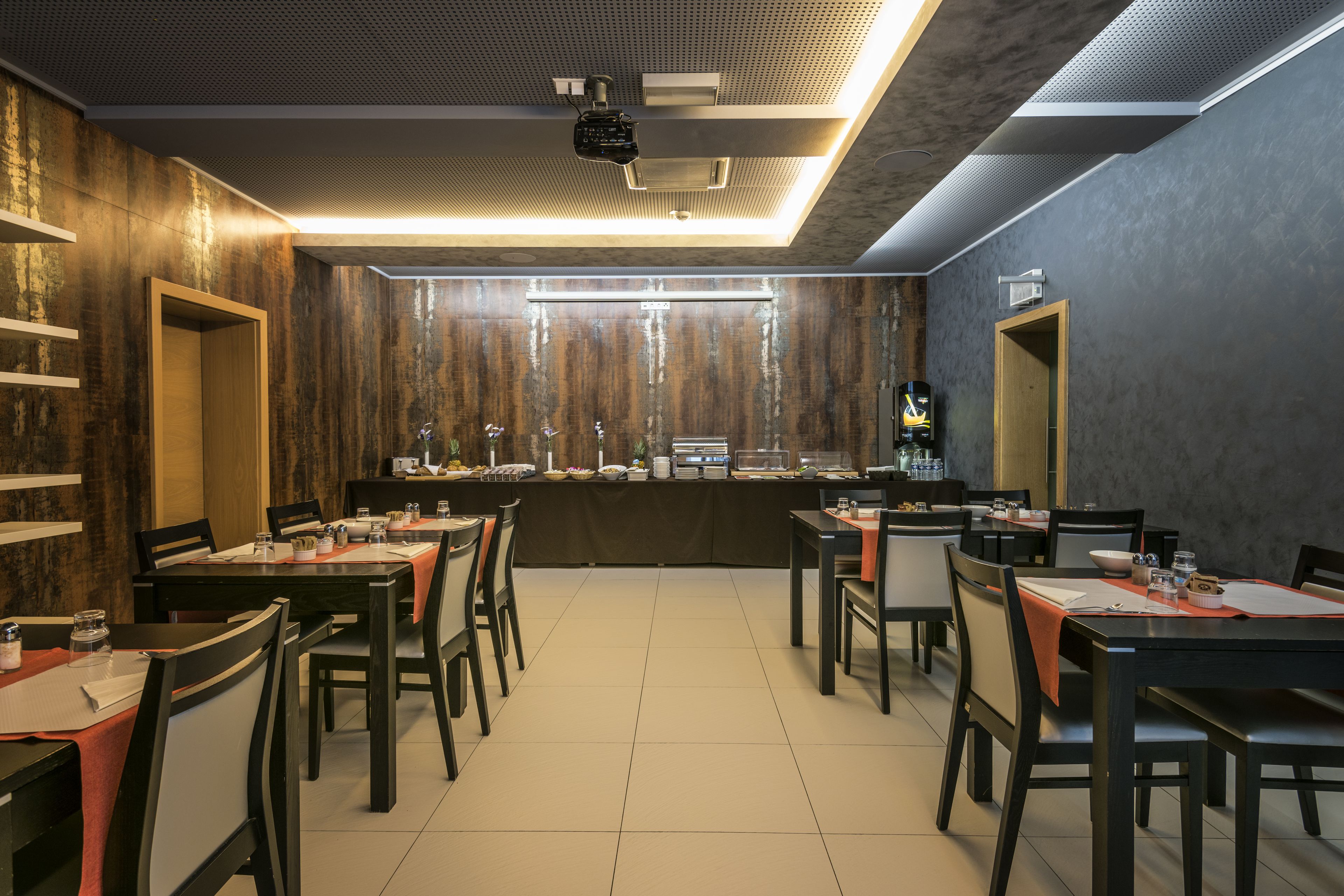 A restaurant with a long counter, multiple tables, and chairs.