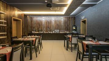 A restaurant with a long counter, multiple tables, and chairs.