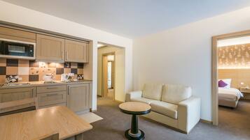 Una habitación de hotel moderna con kitchenette, una mesa redonda, un sofá y una cama.