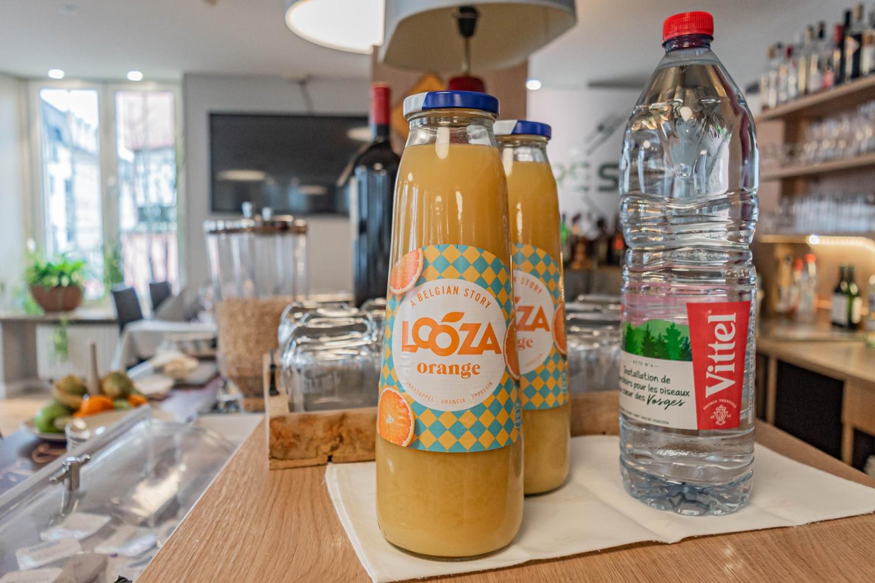 Ein Tisch mit drei Flaschen Lozoa Orangensaft und einer Flasche Vittel Wasser.