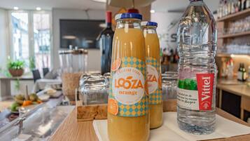 Ein Tisch mit drei Flaschen Lozoa Orangensaft und einer Flasche Vittel Wasser.