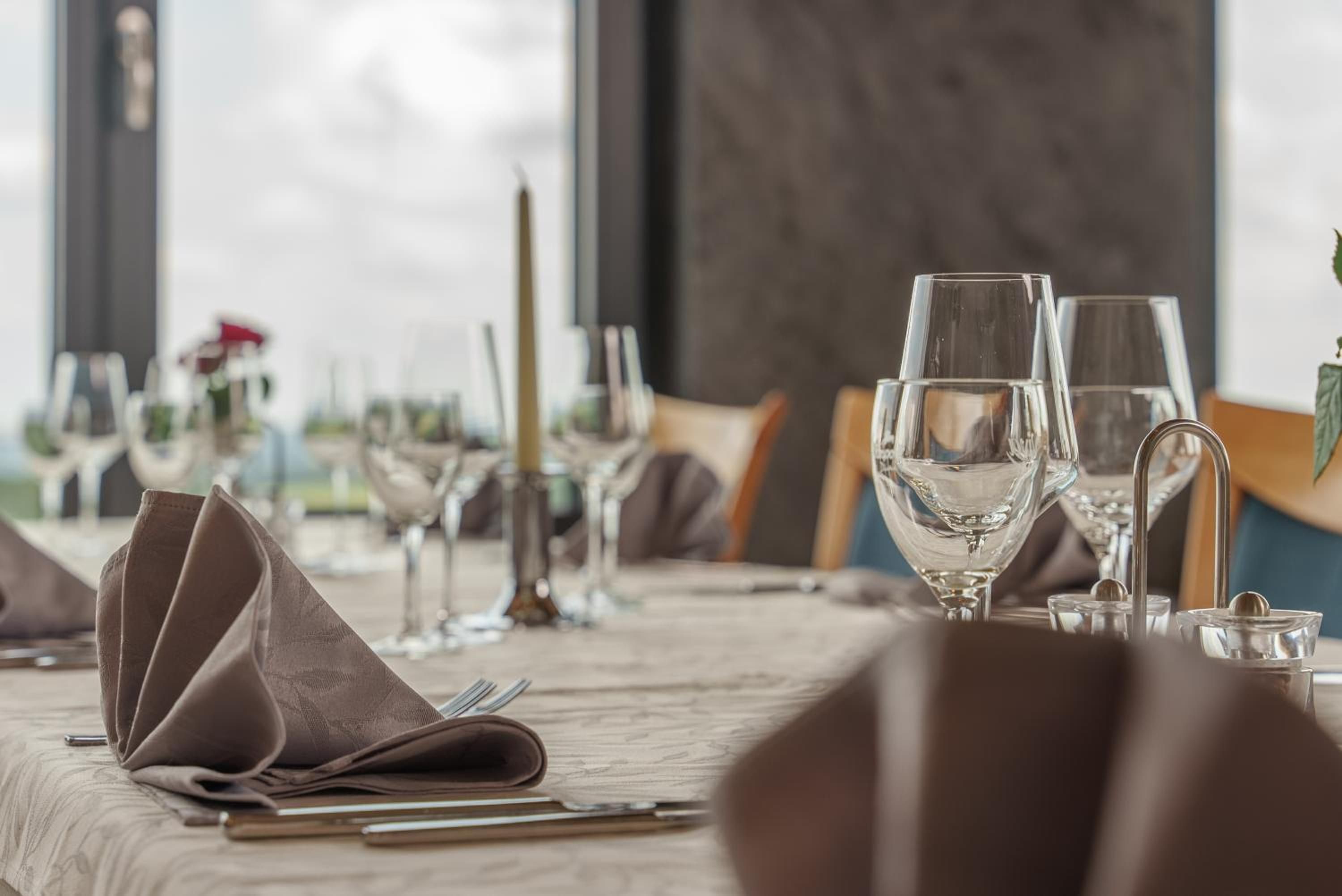 A table set for dining with clear glassware, a folded napkin, and a candle.