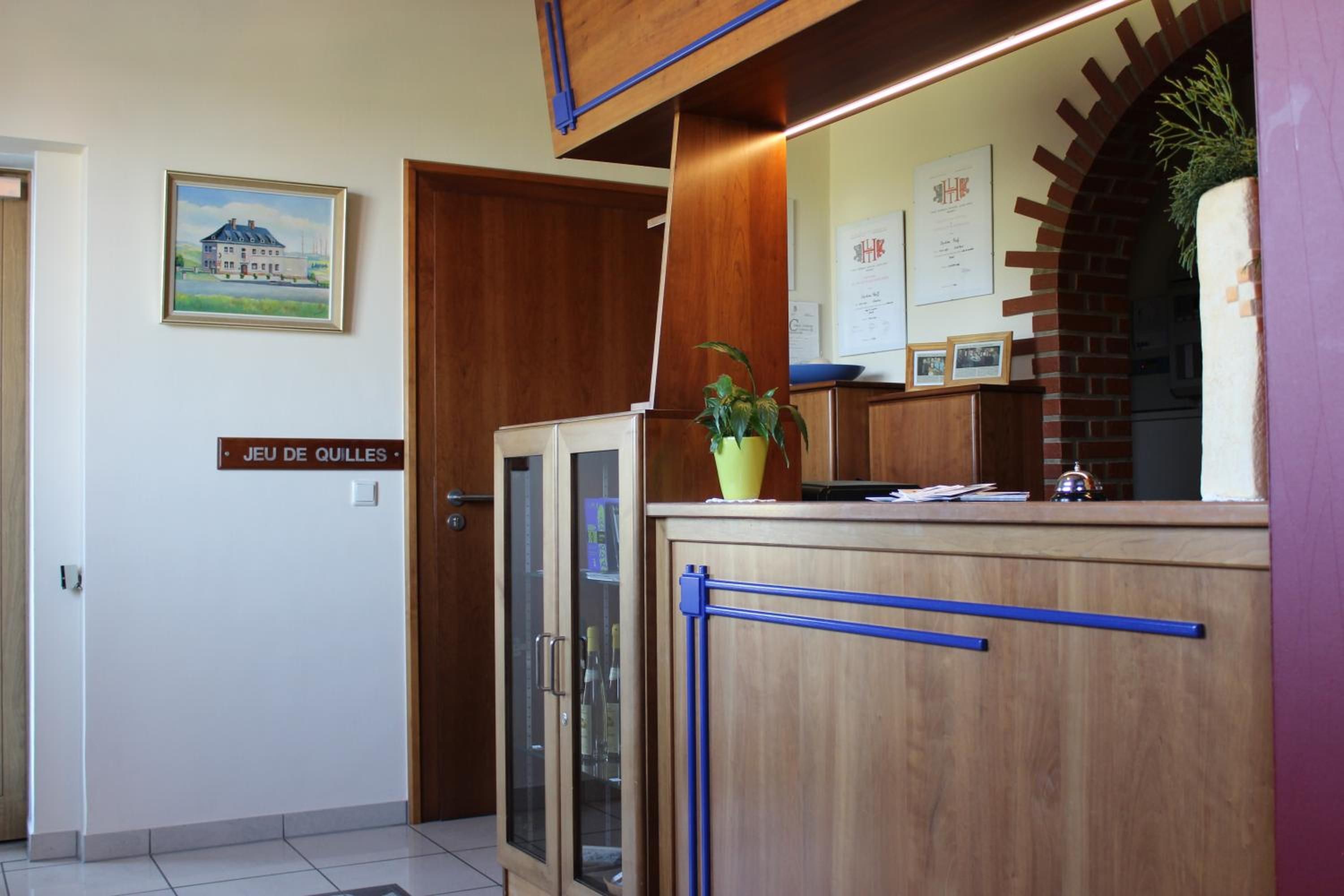 Un área de recepción con un mostrador de madera, una planta en maceta y un cuadro en la pared.