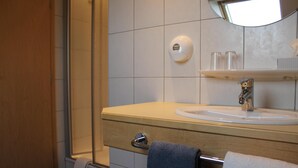 A bathroom with a sink, mirror, towel rack, and a soap dispenser.