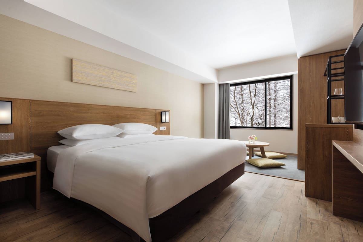 A modern hotel room with a large bed, a desk, and a TV.