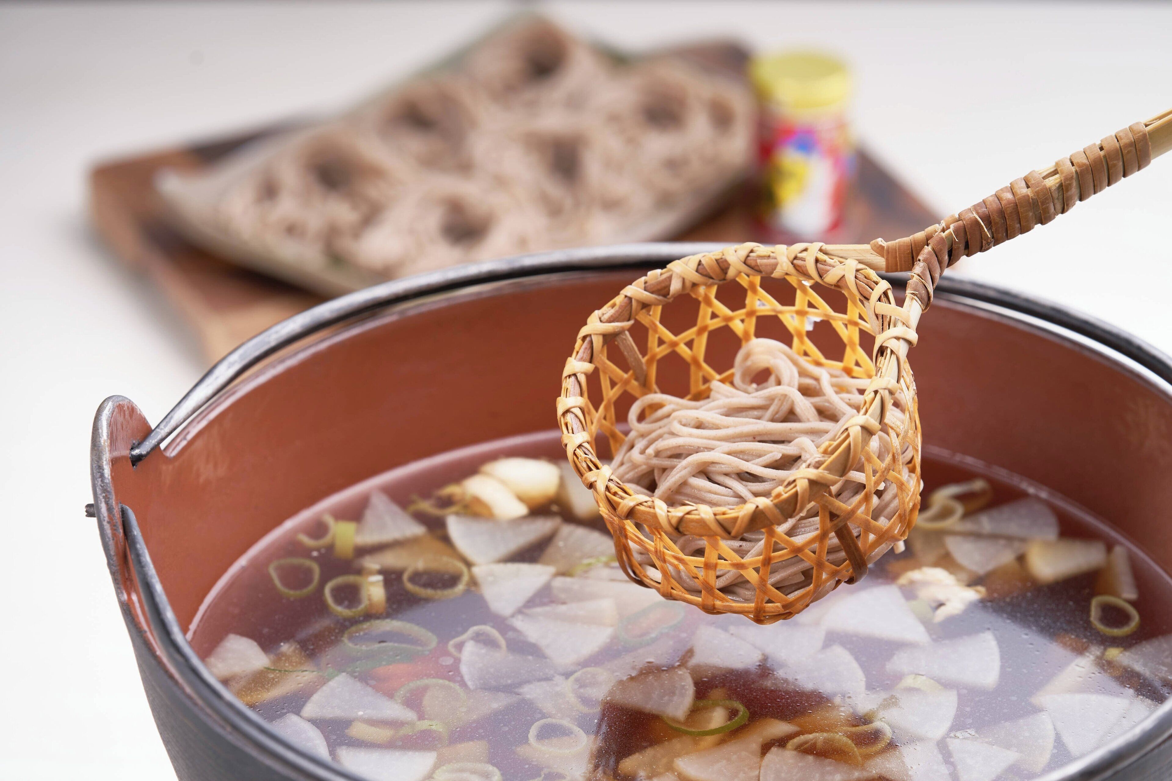 A pot of soup with noodles and vegetables.