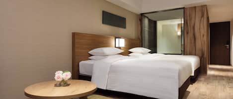 Una habitación de hotel con una cama grande, una mesita de noche con un florero y una pequeña mesa redonda.