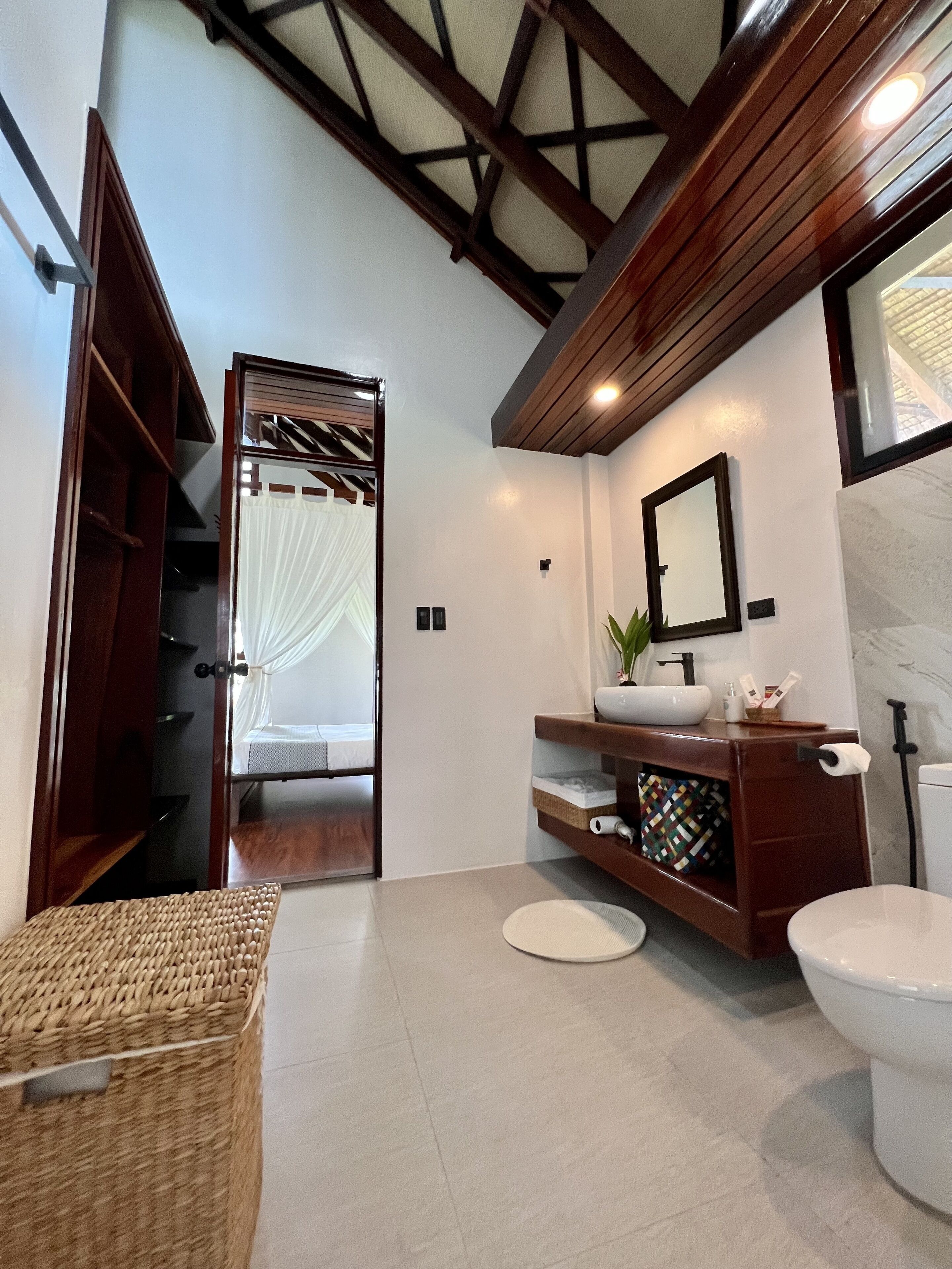 Un baño con tocador de madera, inodoro blanco y zona de ducha.