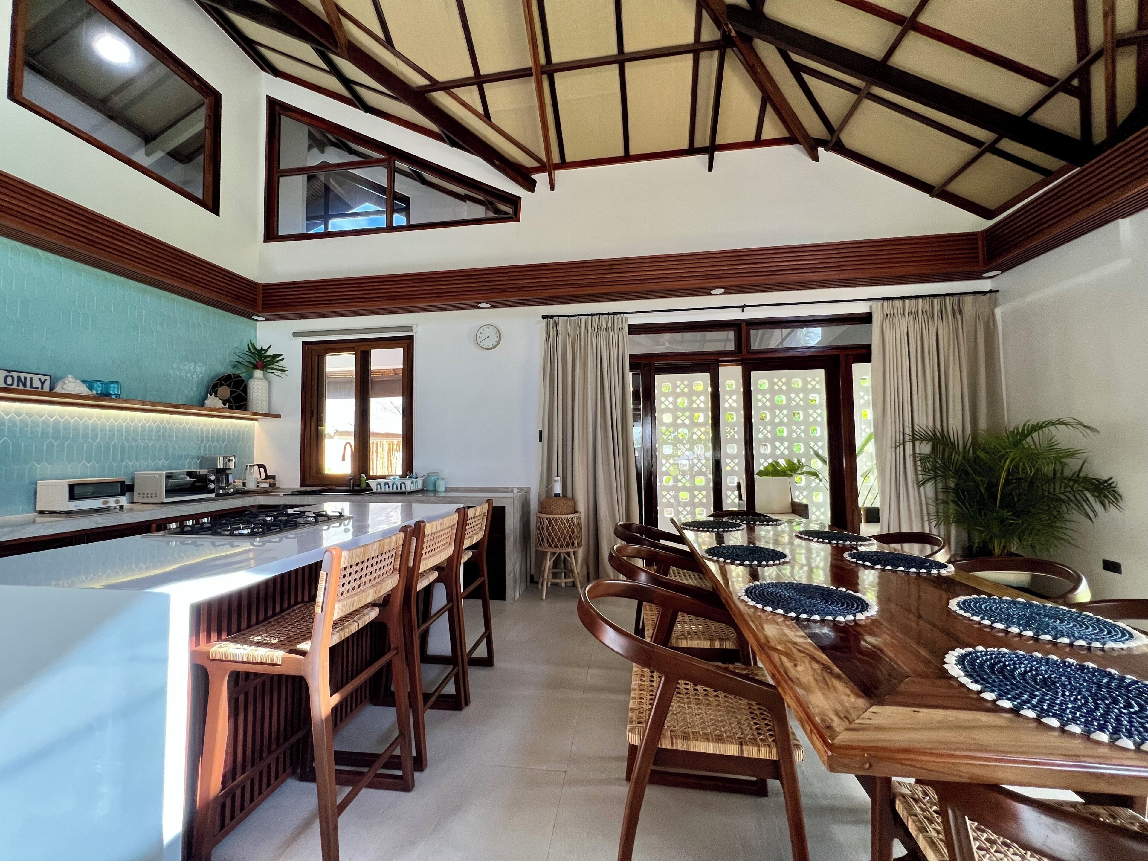 A kitchen with a central island, wooden chairs, and a dining table with placemats.