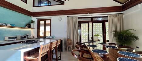 A kitchen with a central island, wooden chairs, and a dining table with placemats.