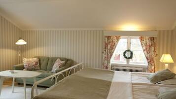 A bedroom with a bed, a sofa, a small table, and a window with curtains.