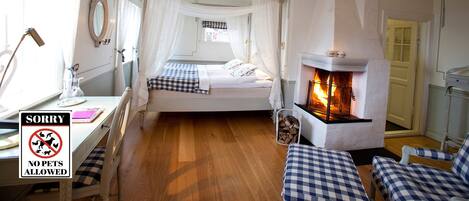 A room with a bed, a fireplace, a desk, and a "No Pets Allowed" sign.