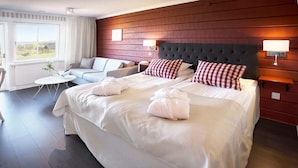 Une chambre d’hôtel avec un grand lit, un canapé, une petite table et une vue sur l’extérieur.