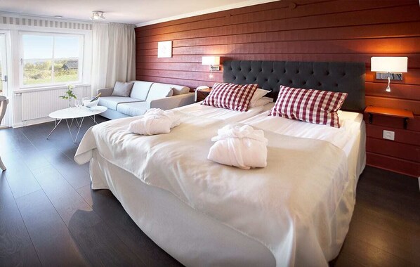 A hotel room with a large bed, a sofa, a small table, and a view of the outdoors.