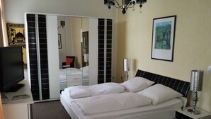 A hotel room with a bed, a TV, a mirror, and a painting on the wall. - Hotel Waldeck (Todtmoos)