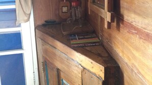A wooden room with a window, a mirror, and a shelf with books. - Le Petit Gili (Gili Trawangan)