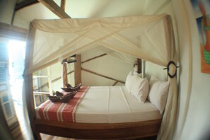 Un lit à baldaquin, avec des poutres en bois et une couverture rayée rouge et blanche.