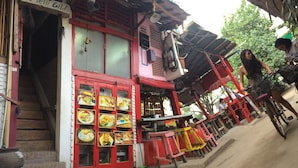 A building with a red facade, a staircase leading to the entrance, and a series of framed pictures on the wall. - Le Petit Gili (Gili Trawangan)