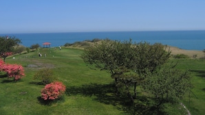 Ein Golfplatz mit einem roten Pavillon, saftigem Grün und Blick aufs Meer.