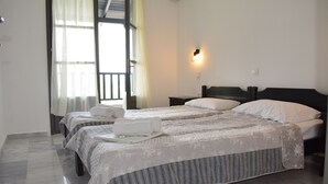 A hotel room with two beds, a nightstand, a wall-mounted light, and a window with curtains.