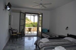 A bedroom with two beds, a desk, and a chair. There is a sliding glass door leading to an outdoor area.
