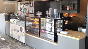 A bakery counter with a display case of pastries and a coffee station.