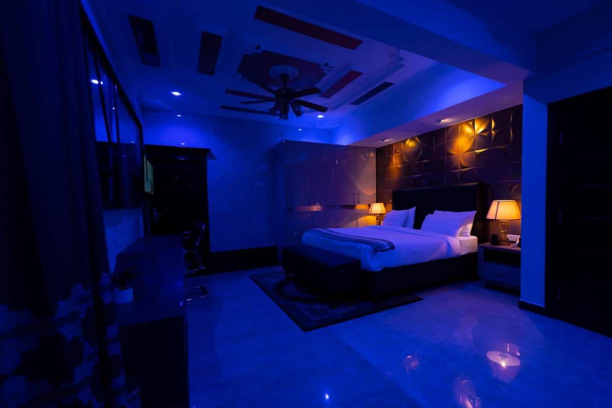 Un dormitorio moderno con cama, lámparas de noche y ventilador de techo.