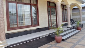 A building with large windows, a tiled entrance, and potted plants.