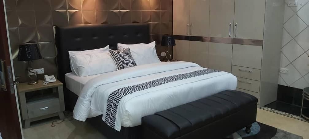Un dormitorio moderno con una cama grande, una mesita de noche con lámpara y un armario.