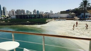 A deck with a view of a beach and a city skyline. - C Hotel (Manama)