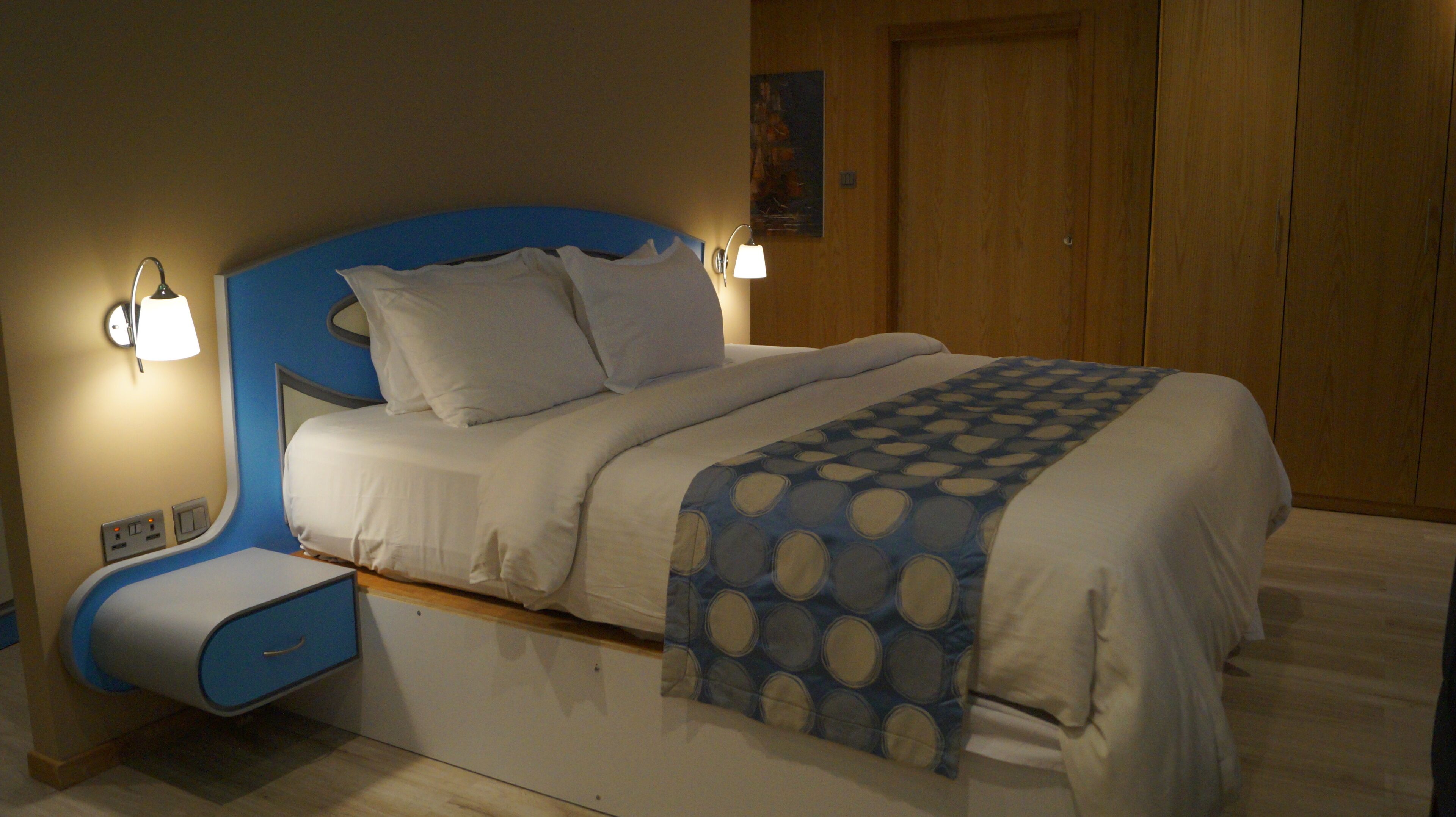 Une chambre à coucher avec un lit, des tables de chevet et une lampe fixée au mur.