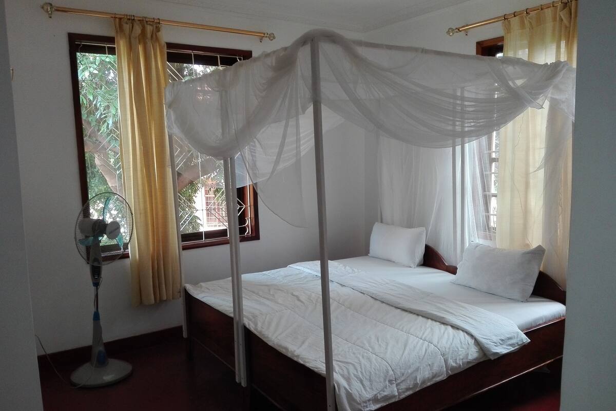 Ein Himmelbett mit einem Ventilator und einem Vorhangfenster.